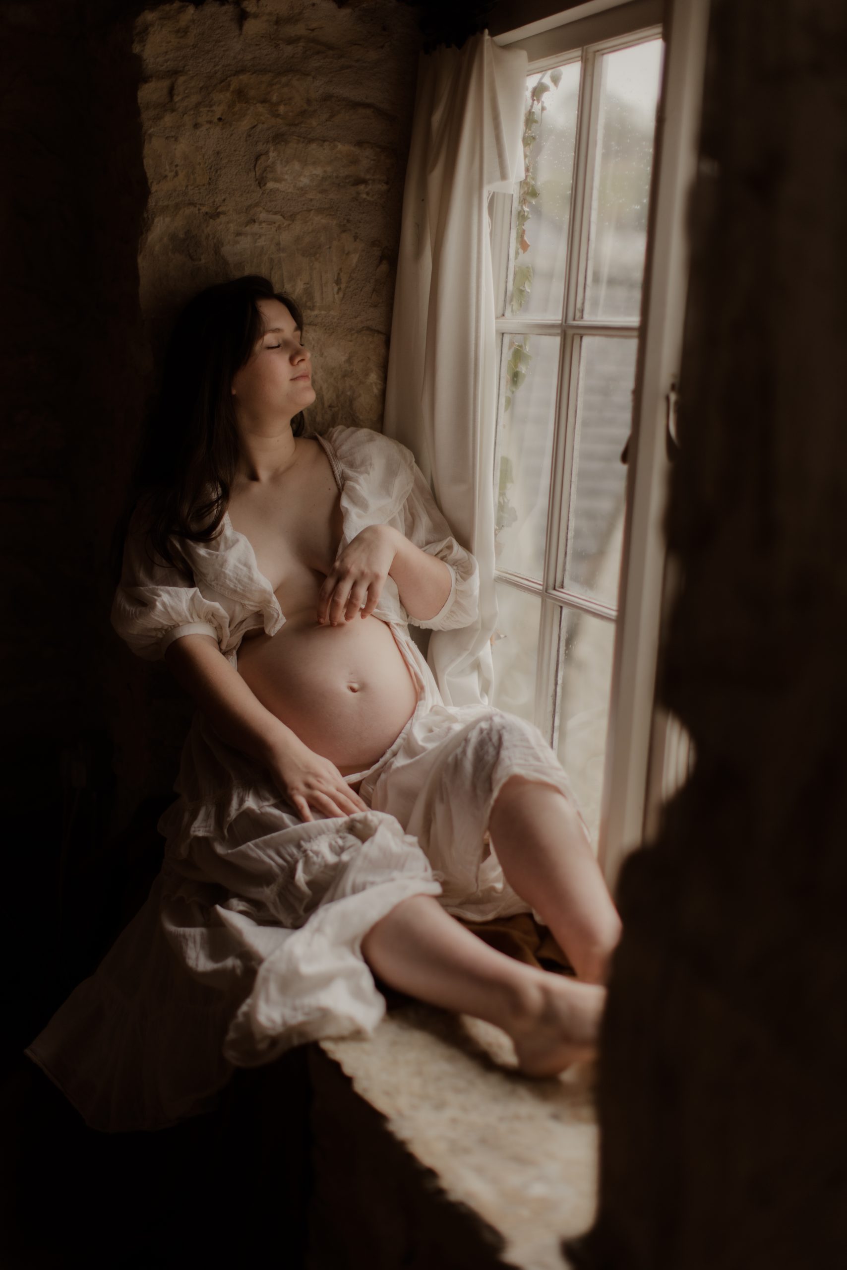 Pregnant mother sitting by the window looking out